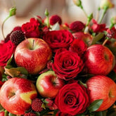 Basket of red apples and roses on a table with a blurred background